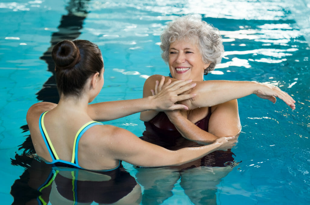 Senior woman stretching in pool