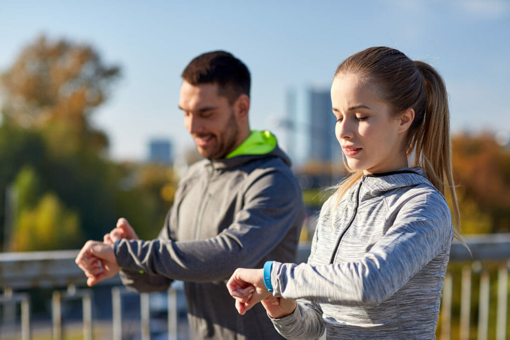 Couple with fitness trackers training in city