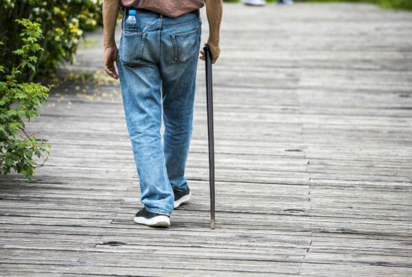 Elderly man with cane on the wood street