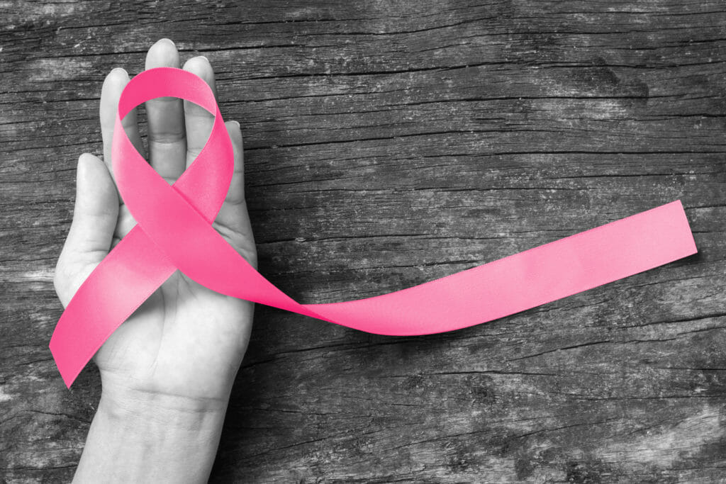 Pink ribbon awareness symbol on woman hand: Symbolic logo icon concept raising awareness campaign on female people living with breast cancer