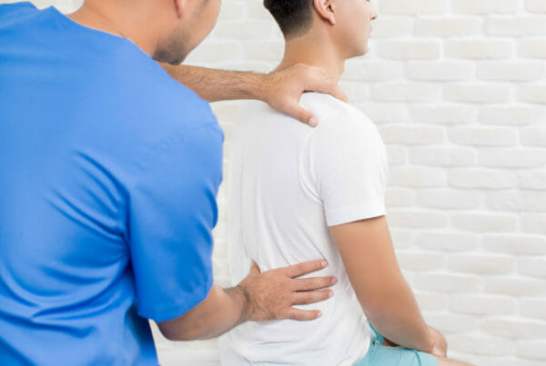 Male doctor therapist treating lower back pain patient in clinic or hospital